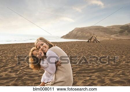 Smiling mother and daughter hugging on beach View Large Photo Image Stock Image - Smiling mother and daughter hugging on beach. Fotosearch