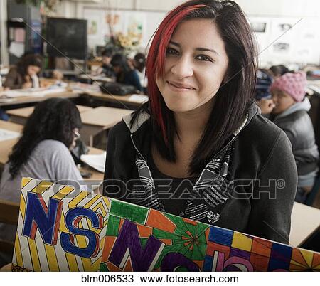 Stock Image - Smiling student holding banner in classroom. Fotosearch