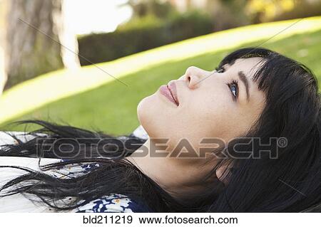 Stock Photo - Smiling woman laying in grass. Fotosearch