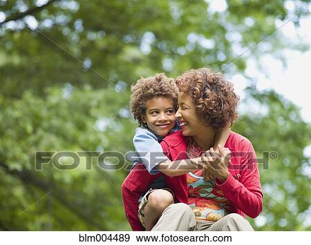 Stock Photo - Son hugging mother outdoors. Fotosearch
