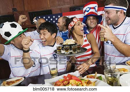 Stock Photo - Sports fans drinking and eating in sports bar. Fotosearch