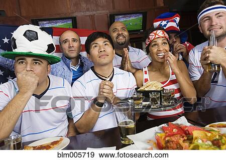 Sports fans drinking and eating in sports bar View Large Photo Image Stock Photo - Sports fans drinking and eating in sports bar. Fotosearch