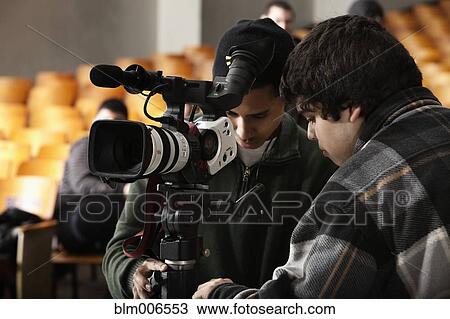 Stock Image - Students adjusting video camera equipment. Fotosearch