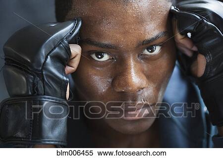Stock Photography - Sweating mixed race man in padded gloves. Fotosearch