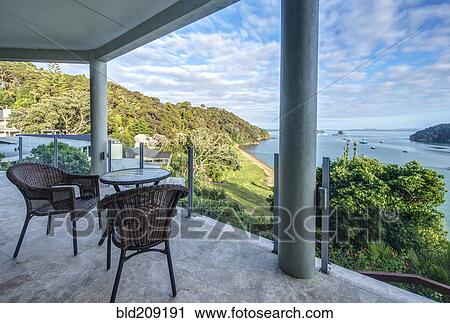 Stock Image - Table and chairs on balcony overlooking Bay of Islands, Paihia, New Zealand. Fotosearch