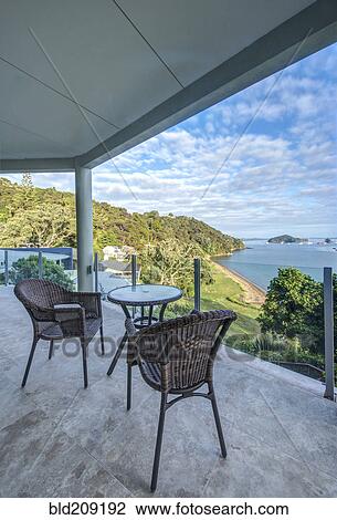 Stock Image - Table and chairs on balcony overlooking Bay of Islands, Paihia, New Zealand. Fotosearch