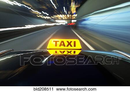 Stock Image - Taxi driving over a motorway at night. Fotosearch