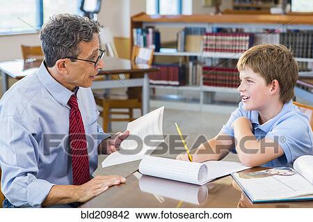 Stock Image - Teacher and student working in library. Fotosearch