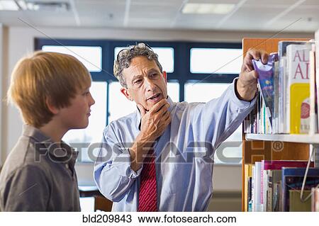 Stock Image - Teacher and student working in library. Fotosearch