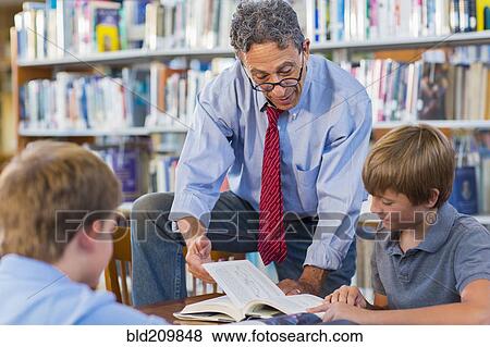 Stock Photo - Teacher and students working in library. Fotosearch