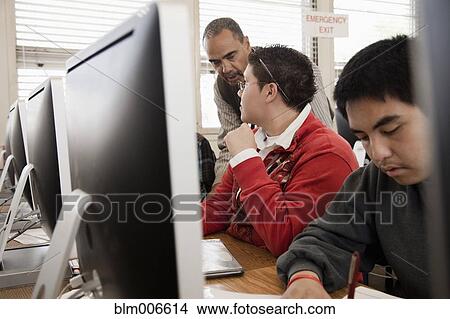 Picture - Teacher helping students in computer lab. Fotosearch