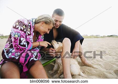 Teenage couple with puppy on beach View Large Photo Image Stock Photograph - Teenage couple with puppy on beach. Fotosearch