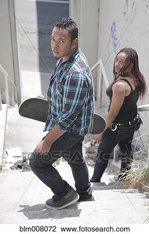 Stock Image - Teenagers holding skateboards on urban stairs. Fotosearch
