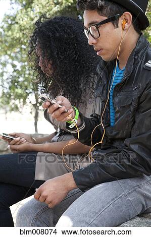 Teenagers listening to headphones and mp3 players View Large Photo Image Picture - Teenagers listening to headphones and mp3 players. Fotosearch