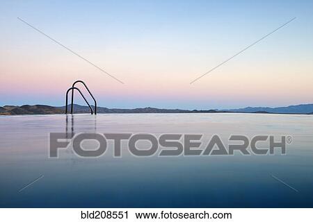 Stock Image - The colors of the setting sun reflecting in an infinity pool overlooking the Andalucian mountains. Fotosearch