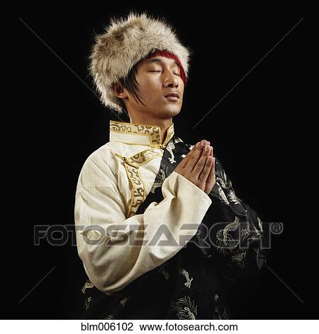 Stock Image - Tibetan man in traditional clothing praying. Fotosearch