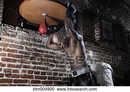 Stock Image - Tired African boxer at speed bag. Fotosearch