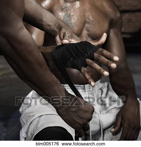 Stock Photograph - Trainer wrapping African boxer's hands. Fotosearch