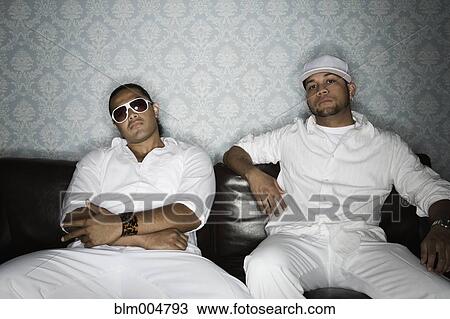 Trendy men sitting on sofa View Large Photo Image Stock Image - Trendy men sitting on sofa. Fotosearch