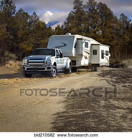 Stock Image - Truck pulling RV trailer on dirt road. Fotosearch