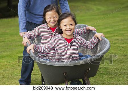 Stock Photo - Twins with Down's Syndrome smiling in wheelbarrow. Fotosearch