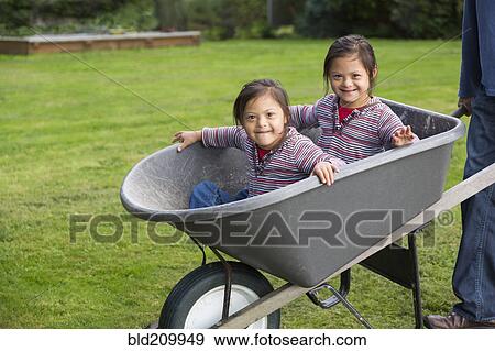 Stock Photo - Twins with Down's Syndrome smiling in wheelbarrow. Fotosearch