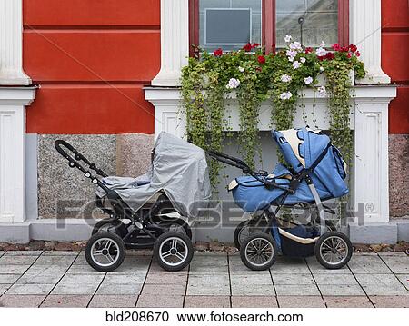 Stock Image - Two prams outside a house, under a window box. Fotosearch