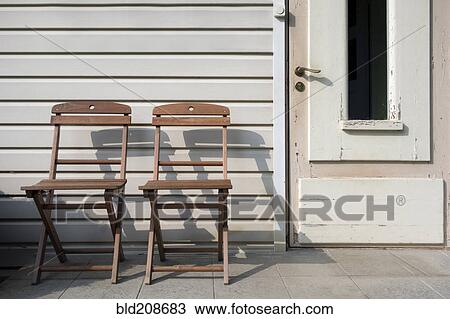 Two wooden chairs outside a house door View Large Photo Image Stock Image - Two wooden chairs outside a house door. Fotosearch