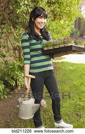 Stock Photograph - Woman carrying flower starts in backyard. Fotosearch