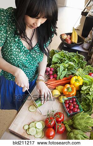 Stock Photo - Woman chopping vegetables in kitchen. Fotosearch