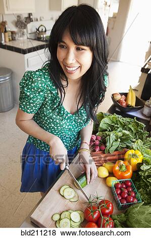 Stock Photo - Woman chopping vegetables in kitchen. Fotosearch