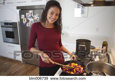 Stock Photo - Woman cooking dinner on stove. Fotosearch