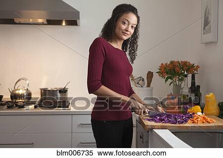 Stock Photography - Woman cutting vegetables in kitchen. Fotosearch