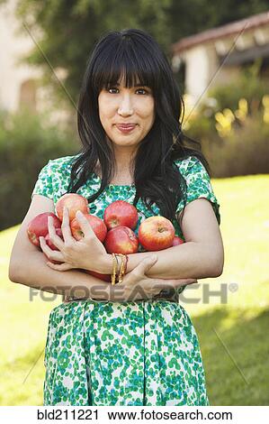 Stock Image - Woman holding armfuls of fruit. Fotosearch