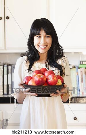 Woman holding bowl of fruit in kitchen View Large Photo Image Stock Image - Woman holding bowl of fruit in kitchen. Fotosearch
