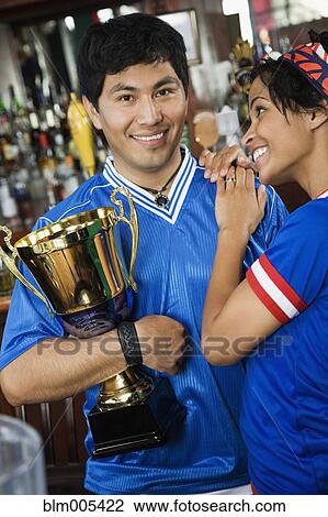 Stock Image - Woman hugging boyfriend with trophy. Fotosearch