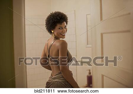 Stock Image - Woman in dress smiling in bathroom. Fotosearch