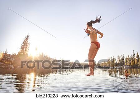 Stock Photo - Woman jumping into rural lake. Fotosearch