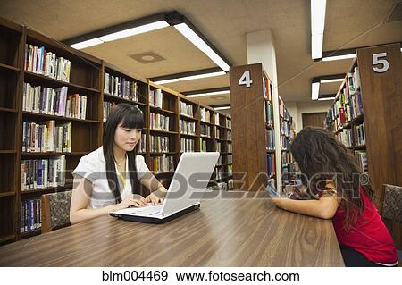 Stock Photo - Woman on laptop and girl on video game in library. Fotosearch