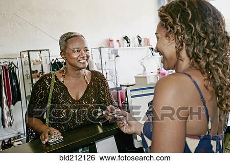 Stock Photograph - Woman paying in store. Fotosearch
