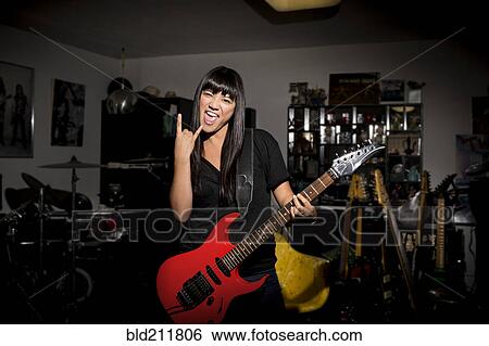 Woman playing electric guitar in basement View Large Photo Image Stock Photograph - Woman playing electric guitar in basement. Fotosearch