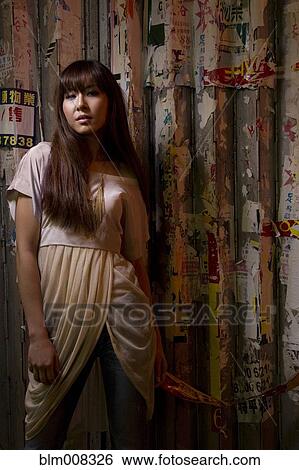 Stock Photograph - Woman standing near wall outdoors. Fotosearch