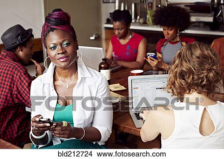 Picture - Woman using cell phone in cafe. Fotosearch