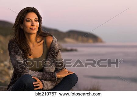 Stock Photo - Woman wrapped in sweater on beach. Fotosearch