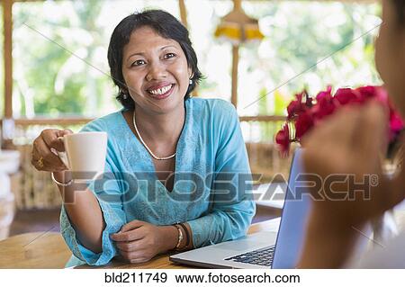 Stock Photo - Women having coffee together in cafe. Fotosearch