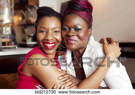 Stock Image - Women hugging in cafe. Fotosearch