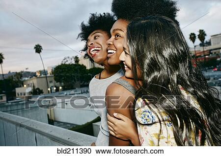 Stock Image - Women laughing together on urban rooftop. Fotosearch