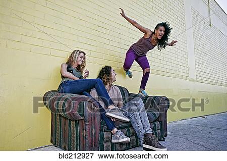 Stock Photo - Women playing on sofa on city street. Fotosearch