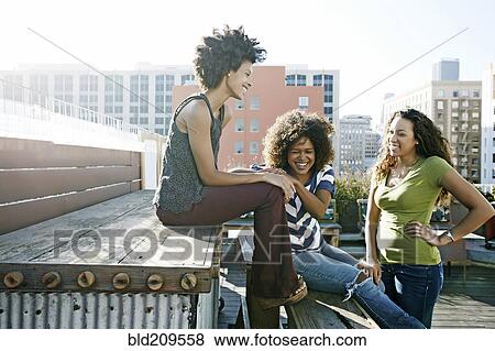 Stock Photo - Women relaxing on urban rooftop. Fotosearch
