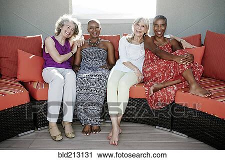 Stock Image - Women relaxing together on urban rooftop. Fotosearch